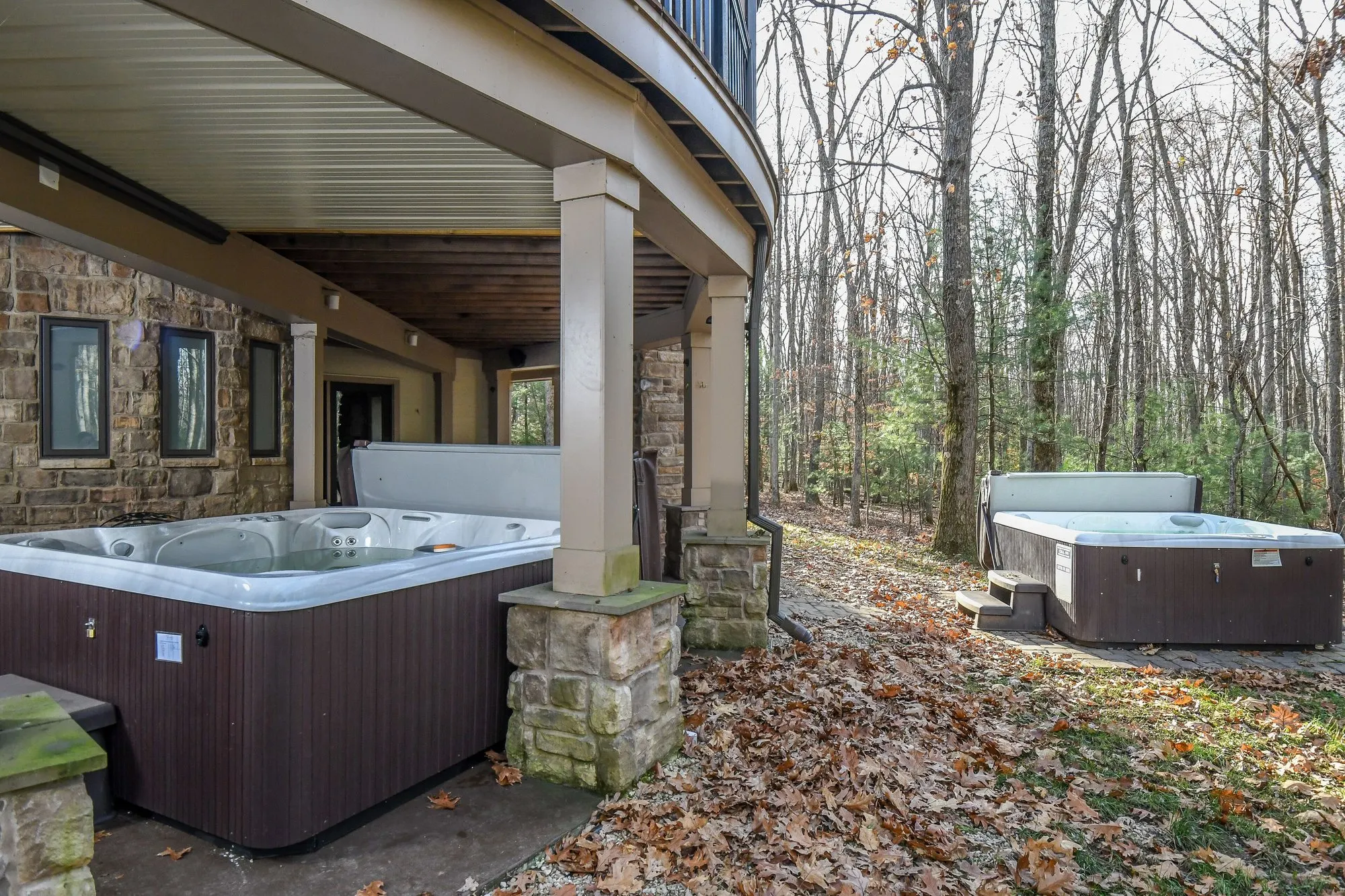 Both hot tubs on the covered patio beside the stone fireplace at Woodland Chalet